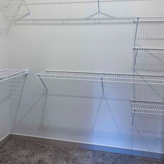 Thumbnail 19 of 29 a walk-in closet with built-in wire shelving and hanging space