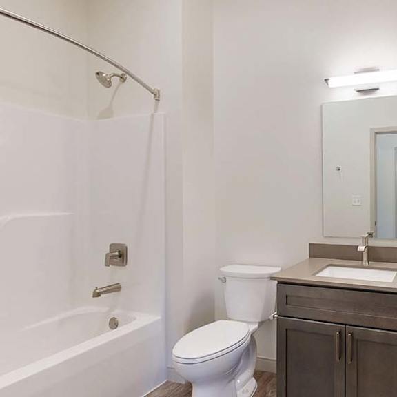 Thumbnail 47 of 50 Apartment bathroom with a single-sink vanity, bathtub and shower, and bright lighting.