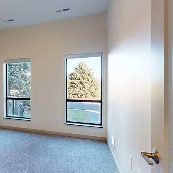 Thumbnail 45 of 50 Bright apartment bedroom with neutral carpet and two large windows.