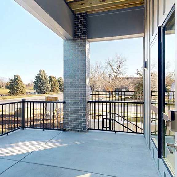 Thumbnail 49 of 50 Covered apartment patio with a private entrance, metal railing, and open neighborhood views.
