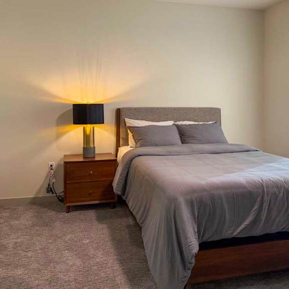 Thumbnail 28 of 42 A bedroom with a large bed and a lamp on the side table.