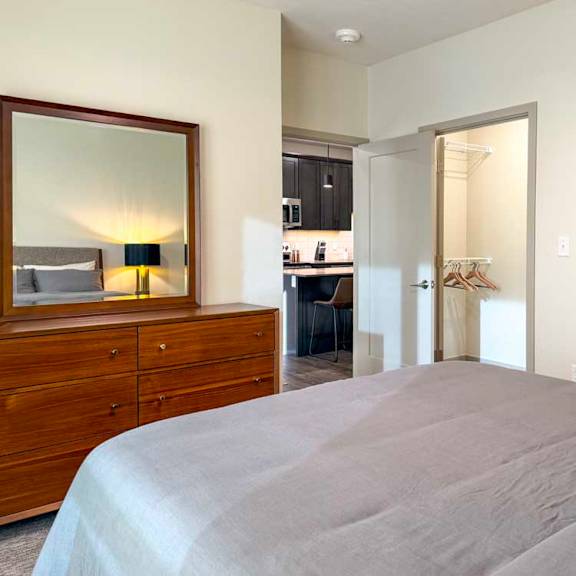 Thumbnail 29 of 42 Bedroom with dresser and mirror, open closet, and view into kitchen.