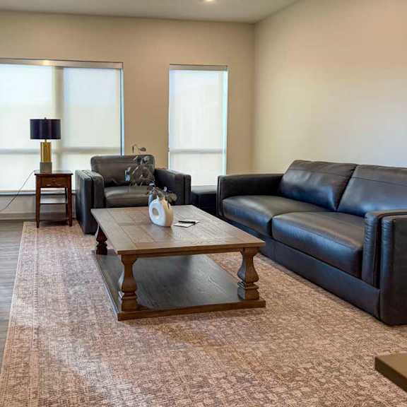 Thumbnail 26 of 42 Living room with sofa, armchair, coffee table, and large windows.