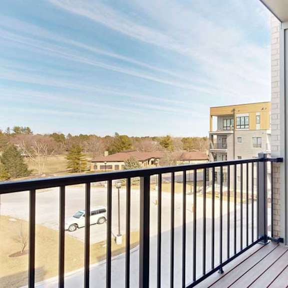 Thumbnail 11 of 21 A balcony with a metal railing, a windowed door to the living room, and a view of the neighborhood.