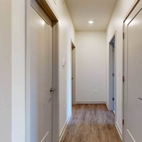 Thumbnail 15 of 21 A hallway with closets on either side.