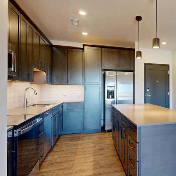 Thumbnail 13 of 21 A front entryway next to a modern kitchen with dark cabinets and stainless steel appliances.