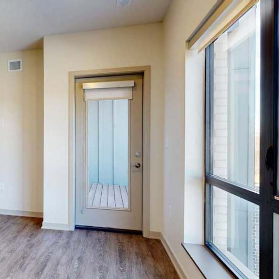 Thumbnail 9 of 21 A living room with hardwood-style flooring, floor-to-ceiling windows, and a windowed door to a balcony.