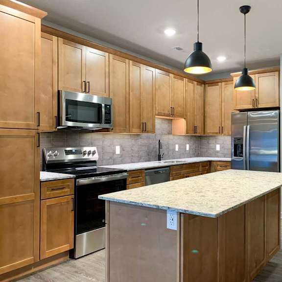 Thumbnail 2 of 25 A kitchen with wooden cabinets and a granite countertop.