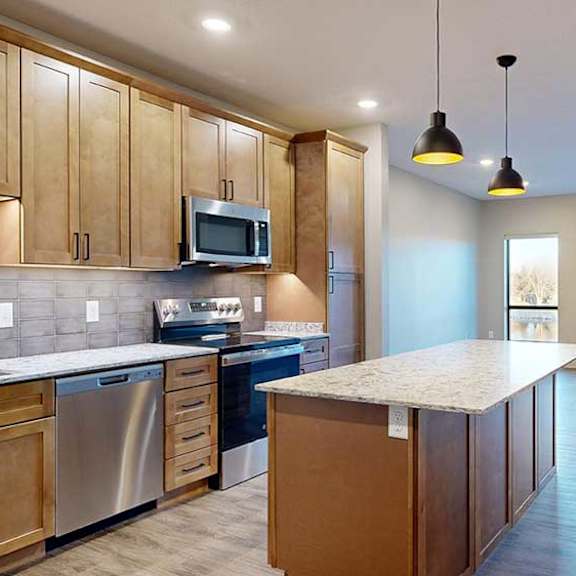 Thumbnail 2 of 26 a kitchen with a large central island featuring tan wooden cabinets and light quartz countertops