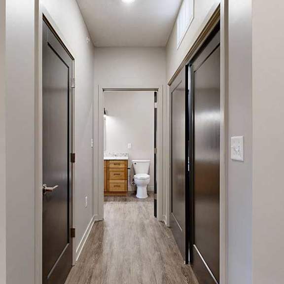 Thumbnail 24 of 26 a hallway with a storage closet and the laundry closet, leading to an open door to the bathroom