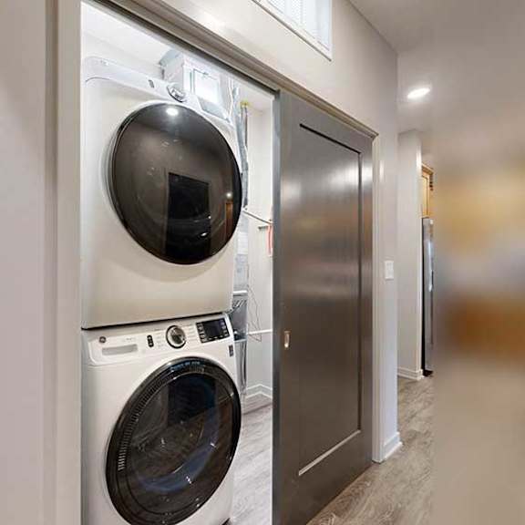 Thumbnail 25 of 26 a two-door laundry closet with stackable, full-sized washer and dryer and extra storage space