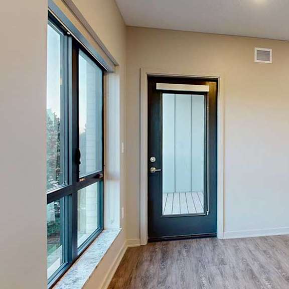 Thumbnail 10 of 26 a living room with hardwood flooring, a large window, and a windowed door to the balcony