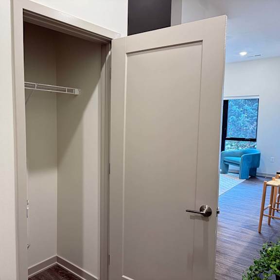 Thumbnail 20 of 20 a hallway with an open door to a closet with a built-in shelf