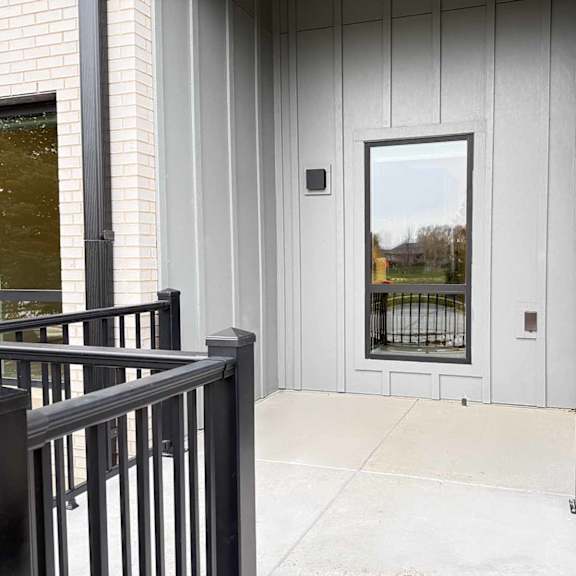 Thumbnail 12 of 20 a walk-out patio with black metal railing and a tall window looking into a kitchen
