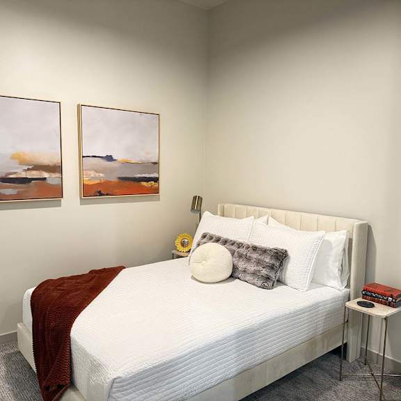 Thumbnail 15 of 20 a sleeping area with a queen bed and two modern paintings on the wall