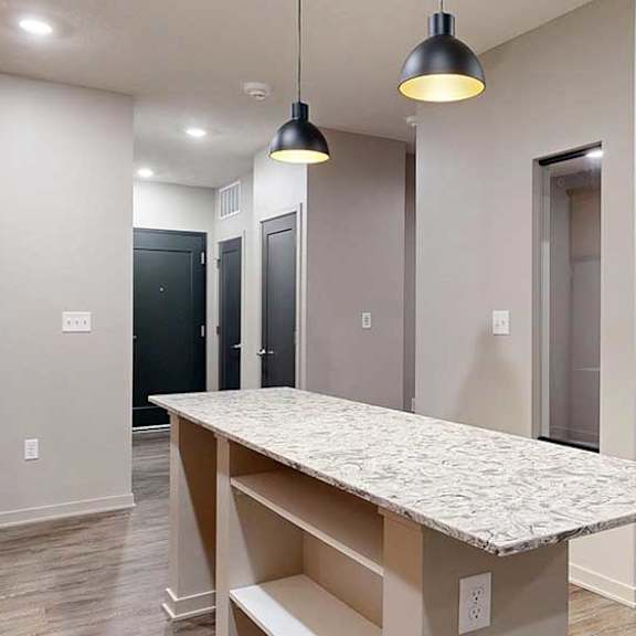 Thumbnail 5 of 20 A kitchen with a table and a refrigerator.