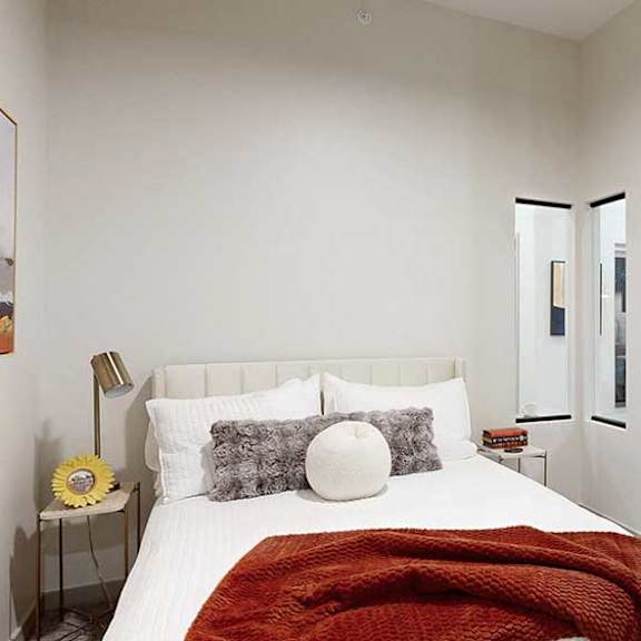 Thumbnail 19 of 22 a bed with a red throw blanket and neutral-toned walls