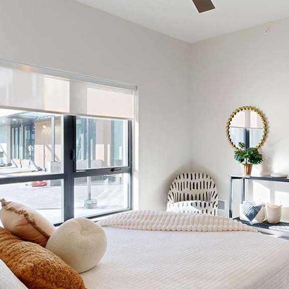 Thumbnail 18 of 26 a bedroom furnished with modern furniture and a large window looking out to the courtyard