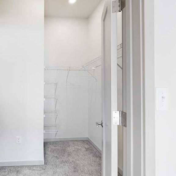 Thumbnail 18 of 23 An L-shaped walk-in closet with several built-in shelves.