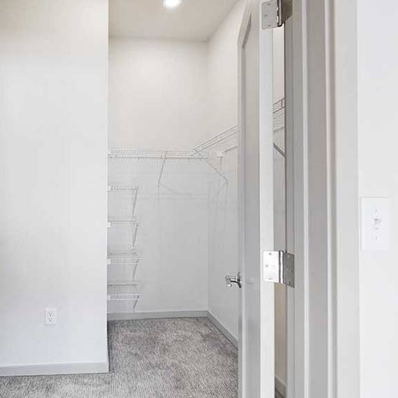 Thumbnail 21 of 26 a spacious L-shaped walk-in closet with built-in shelving and hanging space