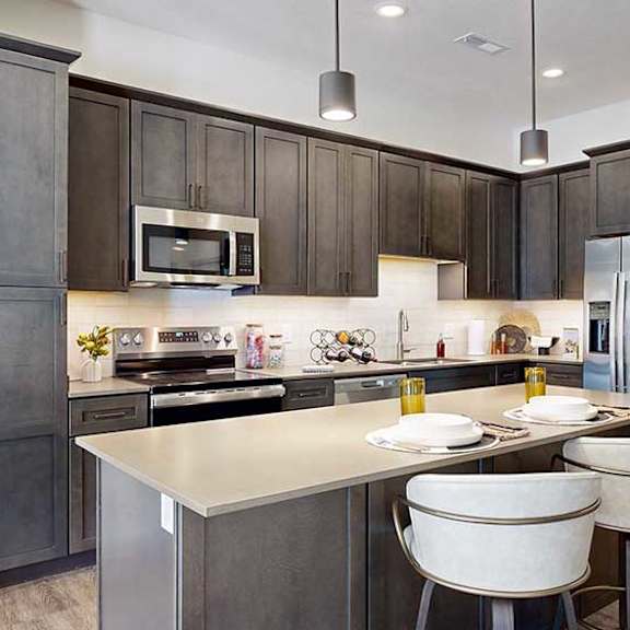 Thumbnail 3 of 26 a modern kitchen with a stainless steel appliances, quartz countertops, a light tile backsplash, dark wooden cabinets, and a large central island