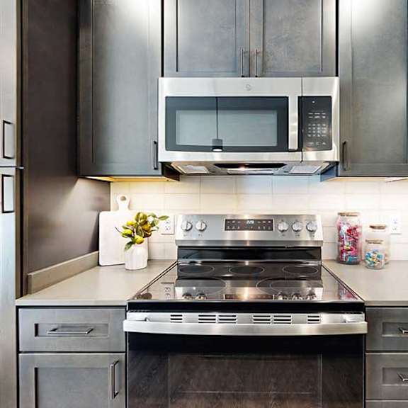Thumbnail 7 of 26 a modern kitchen with a stainless steel appliances, quartz countertops, a light tile backsplash, and dark wooden cabinets