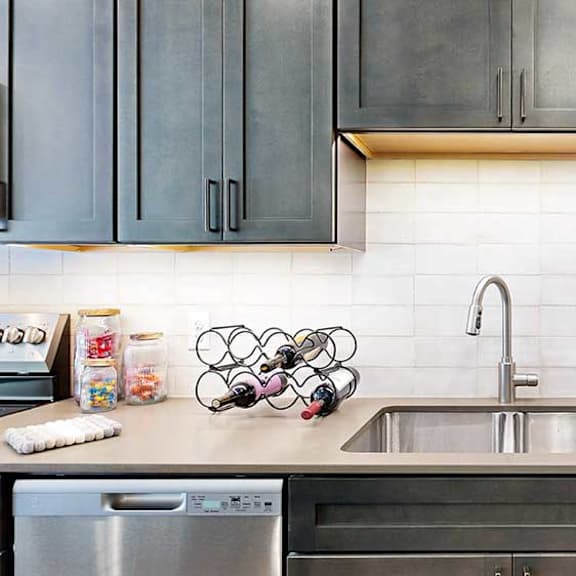 Thumbnail 4 of 23 A modern kitchen sink with quartz counters, dark wooden cabinets, and a tile backsplash.