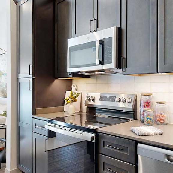 Thumbnail 5 of 23 A close up of the stainless steel microwave and range in a kitchen with dark wooden cabinets.