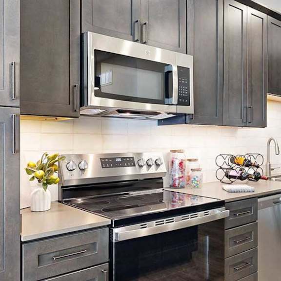 Thumbnail 8 of 26 a modern kitchen with a stainless steel appliances, quartz countertops, a light tile backsplash, and dark wooden cabinets