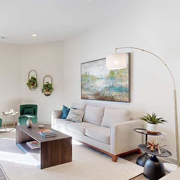 Thumbnail 9 of 23 A living room with a white couch, two green arm chairs, and several modern furnishings.
