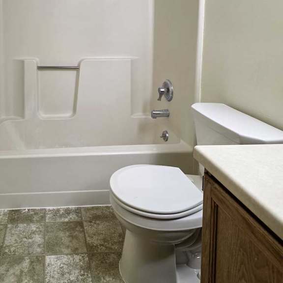 Thumbnail 6 of 11 A bathroom with a sink, and a white tub shower with chrome finishes.
