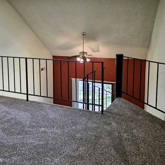 Thumbnail 8 of 11 A loft area with a spiral staircase and a black metal railing.