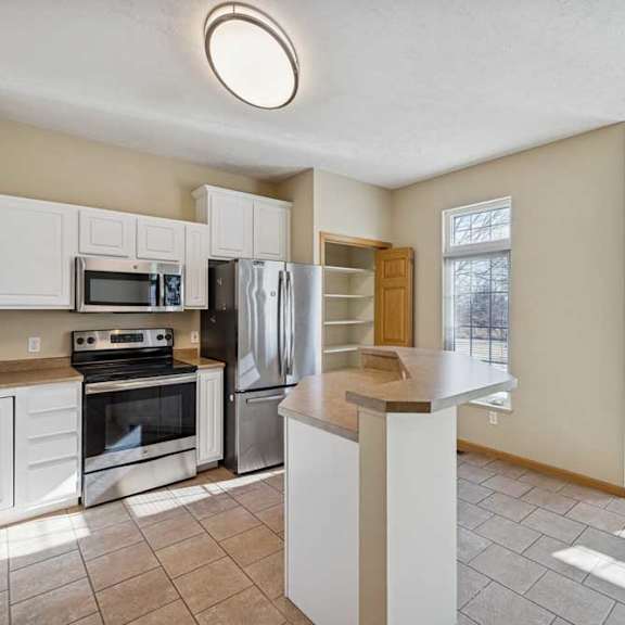 Thumbnail 32 of 54 A kitchen with white cabinets and a black fridge.