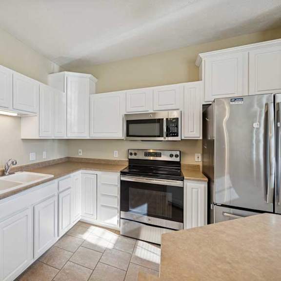 Thumbnail 29 of 54 A kitchen with white cabinets and appliances.