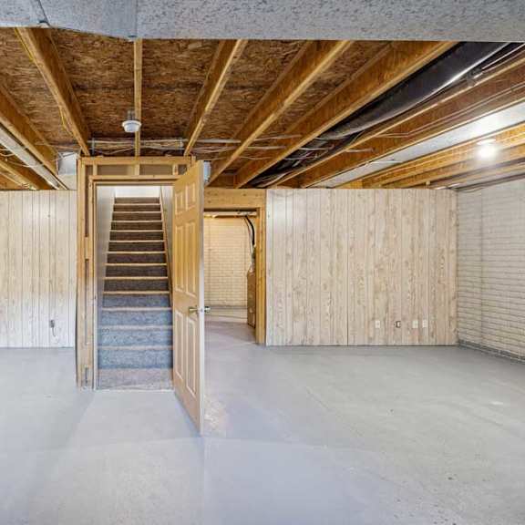 Thumbnail 17 of 79 A spacious attic room with wooden beams and a central staircase.