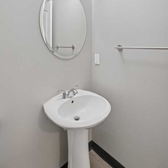 Thumbnail 29 of 79 A white pedestal sink with a round mirror above it.
