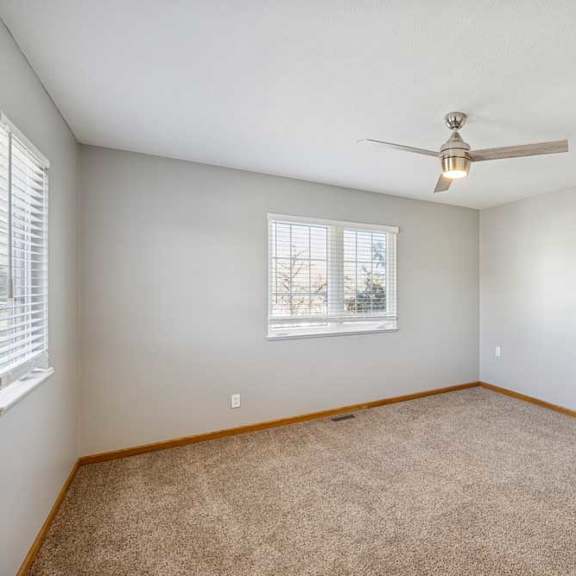 Thumbnail 24 of 79 A room with a ceiling fan and carpeted floor.