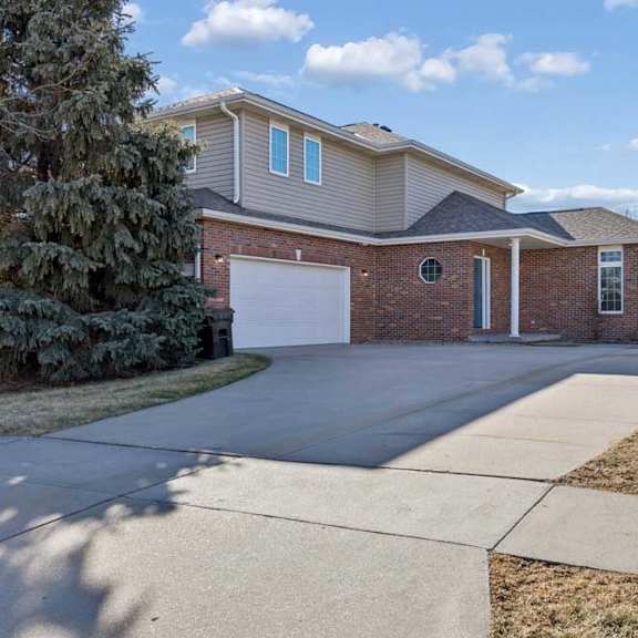 Thumbnail 19 of 79 A two-story house with a garage is surrounded by a well-maintained lawn and a sidewalk.