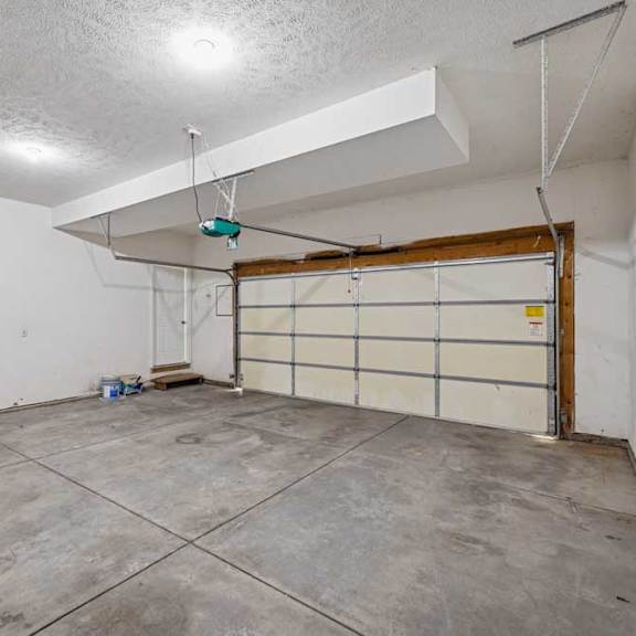 Thumbnail 14 of 79 A garage with a white wall and a brown door.