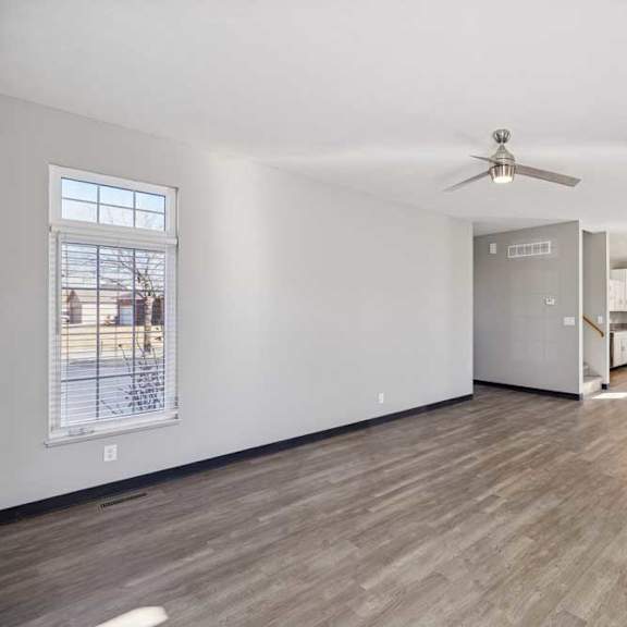 Thumbnail 30 of 79 A spacious room with a ceiling fan and wooden flooring.