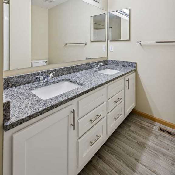 Thumbnail 71 of 79 A bathroom with a granite countertop and a vanity with a sink and mirror.