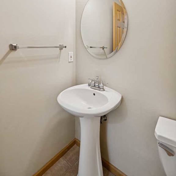 Thumbnail 57 of 79 A white pedestal sink under a round mirror with lights above it.