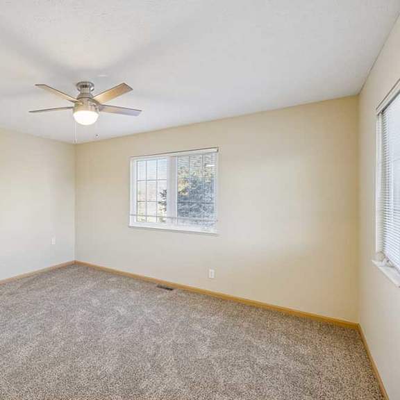 Thumbnail 76 of 79 A room with a ceiling fan and a window with a view of trees.