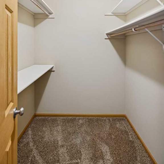 Thumbnail 72 of 79 A small, empty room with a carpeted floor and a wooden door.
