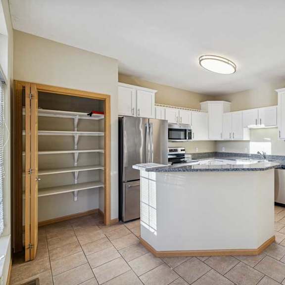 Thumbnail 62 of 79 A kitchen with a white island and stainless steel appliances.