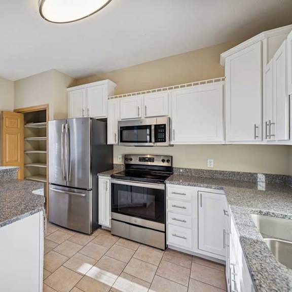 Thumbnail 74 of 79 A kitchen with granite countertops and stainless steel appliances.