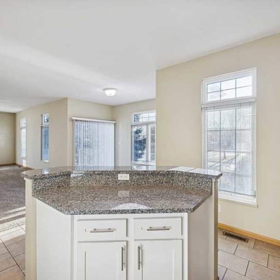 Thumbnail 70 of 79 A kitchen with granite countertops and white cabinets.