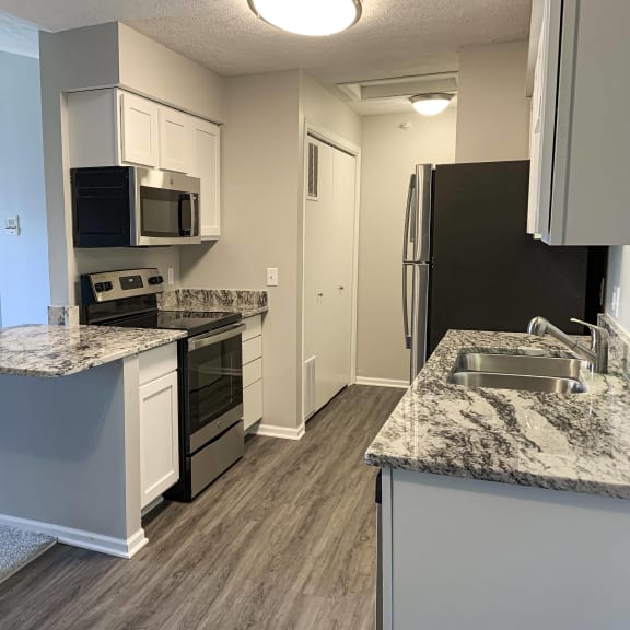Thumbnail 2 of 22 Renovated kitchen with white cabinets and stainless steel appliances at Eagle Run Apartments in Omaha Nebraska