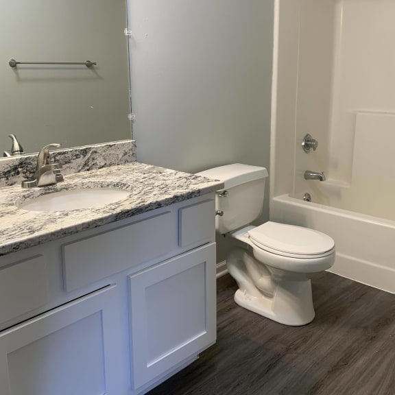 Thumbnail 10 of 22 Bathroom with white vanity for storage and large mirror with great lighting at Eagle Run Apartments in Omaha Nebraska