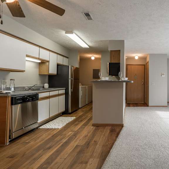 Thumbnail 16 of 22 A kitchen with wooden floors that opens to living room